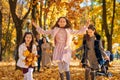 happy children playing together and scattering yellow leaves, portrait of big family in autumn city park, children running with