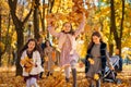 happy children playing together and scattering yellow leaves, portrait of big family in autumn city park, children running with