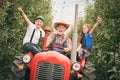 Happy children ride on a tractor with grandpa