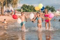 Happy children running together with balloons through the water Royalty Free Stock Photo