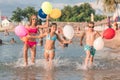 Happy children running together with balloons through the water Royalty Free Stock Photo