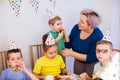 Happy children`s birthday. Mother with little son enjoying birthday party. Kids in festive hats having fun at home Royalty Free Stock Photo