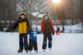 Happy children, skating on a frozen lake in the park