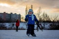 Happy children, skating on a frozen lake in the park