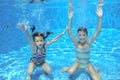 Happy children swim in pool underwater, girls swimming