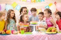 Children at table celebrating birthday holiday. Kids blows together candles on festive cake Royalty Free Stock Photo