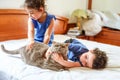 Happy kids with their pet laying on the bed. Royalty Free Stock Photo