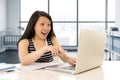 Happy chinese asian woman working and studying on her computer sitting at modern office desk smiling cheerful Royalty Free Stock Photo