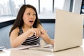 Happy chinese asian woman working and studying on her computer sitting at modern office desk smiling cheerful Royalty Free Stock Photo