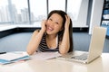 Happy chinese asian woman working and studying on her laptop computer sitting at modern office Royalty Free Stock Photo