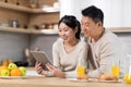 Happy chinese family using digital tablet while having breakfast Royalty Free Stock Photo