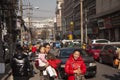 A happy Chinese family walking in a busy street in Beiling, China together with other people, cars and mopeds
