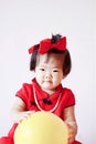 Happy Chinese little baby in red cheongsam play yellow balloon Royalty Free Stock Photo