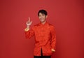 Happy Chinese new year 2024. Asian man wearing red traditional costume and hands pointing finger up isolated on red copy space Royalty Free Stock Photo