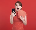 Happy chinese new year. suprised young Woman holding Red envelopes for lucky and watching the mobile phone Royalty Free Stock Photo