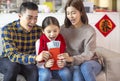 Happy chinese new year. surprised parent and child watching the red envelope with money. chinese text: spring time Royalty Free Stock Photo