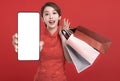 Happy chinese new year. Happy young Woman showing blank smart phone screen and shopping bags Royalty Free Stock Photo