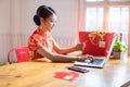 Happy chinese woman wearing a qipao dress traditional and buying online with a red credit card. Online Shopping Website on Laptop Royalty Free Stock Photo