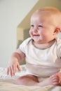 Happy chubby baby sitting on bed