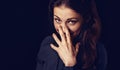 Happy chuckling fun business beautiful woman covering the mouth the hand on blue shirt on black background with empty copy space.