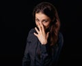 Happy chuckling fun business beautiful woman covering the mouth the hand on blue shirt on black background with empty copy space.