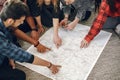 Group of diverse friends looking at map in the bright room