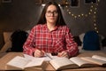 Happy clever caucasian female student in casual wear, sits at the table with books in the university dormitory, takes