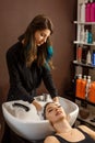 Happy client in a hair salon who wash her hair with shampoo Royalty Free Stock Photo