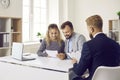 Clients sitting at desk in real estate agent's office and reading contract that he gave them Royalty Free Stock Photo