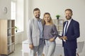 Happy clients together with real estate agent or mortgage broker standing in office and smiling Royalty Free Stock Photo