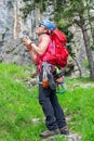 Happy climber girl with a red backpack, quickdraws, climbing shoes, chalk bag attached to her harness, making a wish Royalty Free Stock Photo