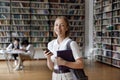 Happy college student girl using mobile phone in public library Royalty Free Stock Photo