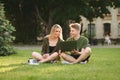 Happy college students communicating, talking, using laptop on campus lawn. Young cheerful caucasian couple of students watching Royalty Free Stock Photo