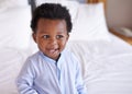 Happy, colors and baby laughing in bed, waking up and playing in his home. Face, smile and african boy toddler in a Royalty Free Stock Photo