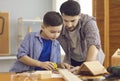 Happy concentraited father and son measuring wooden details for making birdhouse Royalty Free Stock Photo