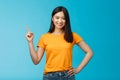 Happy confident asian girl self-assured pointing upper left corner, show way, smiling determined, assertive introduce Royalty Free Stock Photo