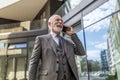 Happy confident businessman talking on mobile phone against office building Royalty Free Stock Photo