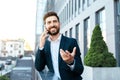 Happy confident european millennial bearded businessman in suit speaks by phone and gesticulates Royalty Free Stock Photo