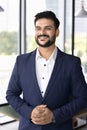 Happy confident Indian company CEO man standing in office