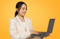 Happy confident japanese millennial woman in suit typing on laptop, enjoy chatting