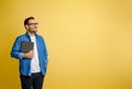 Happy confident male entrepreneur holding digital tablet and contemplating over yellow background Royalty Free Stock Photo