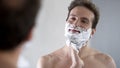 Happy and confident male putting shaving cream on his face before shaving Royalty Free Stock Photo