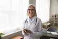 Happy confident senior doctor woman holding mobile phone Royalty Free Stock Photo