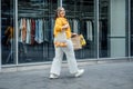 Happy confident smiling plus size curvy young woman with shopping bags walking on city street near shop windows Royalty Free Stock Photo