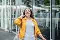 Happy confident smiling plus size curvy young woman with shopping bags walking on city street near shop windows Royalty Free Stock Photo