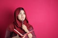 Happy confident successful Asian muslim woman wearing hijab  writing on book, smiling and thinking Royalty Free Stock Photo