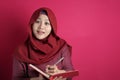 Happy confident successful Asian muslim woman wearing hijab  writing on book, smiling and thinking Royalty Free Stock Photo