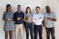 Happy confident successful multiethnic workers standing near wall. Royalty Free Stock Photo