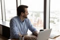 Happy confident thoughtful businessman using laptop, looking out office window Royalty Free Stock Photo