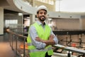 Happy confident young attractive arabic engineer in hard hat and protective clothing in office plant interior Royalty Free Stock Photo